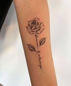 a black and white rose tattoo on the right arm with words written in cursive writing