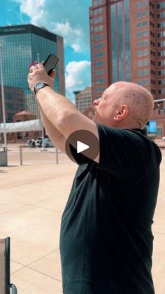 a man taking a selfie with his cell phone in front of some tall buildings