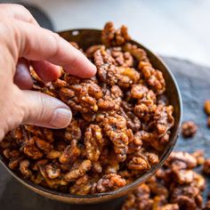 a person is picking up nuts from a bowl