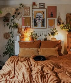 a bed with an orange comforter and some plants on the headboard in front of it