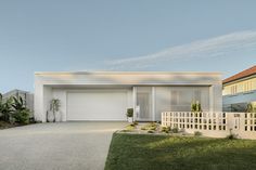 a house with a white fence in front of it and some plants on the lawn