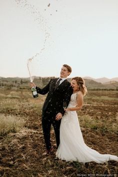 a newly married couple standing in the middle of an open field with confetti