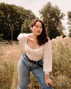 a woman is posing in the middle of some tall grass