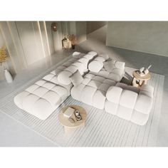 a large white couch sitting on top of a rug next to a table and vases