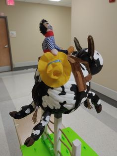 a statue of a man riding on the back of a black and white spotted cow