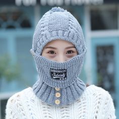 a woman wearing a gray knitted hat and scarf over her face, with the label on it