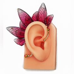 a pink flower shaped earring with leaves on it's back and two piercings in the middle