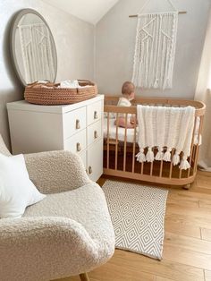 a baby sitting in a crib next to a dresser with a mirror on it