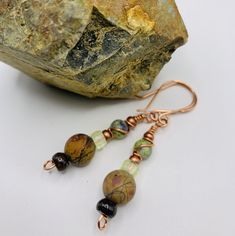 Fall colors of green, brown, earth tone bead with colors of reds, orange, black, dark blue, copper seed bead accents, dark brown doughnut bead at the bottom with handcrafted french ear wires. Adjustable Earthy Beaded Earrings As Gift, Earthy Beaded Dangle Earrings As Gift, Brown Wire Wrapped Drop Beaded Earrings, Brown Wire Wrapped Drop Earrings, Bohemian Brown Hand Wrapped Earrings, Bohemian Brown Hand-wrapped Earrings, Bohemian Hand Wrapped Brown Earrings, Adjustable Green Beaded Earrings With Natural Stones, Brown Earrings With Natural Stones And Round Beads