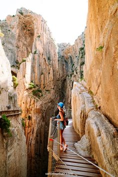 a woman standing on a wooden bridge over a canyon