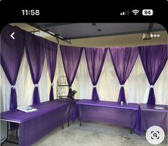 a room with purple and white drapes on the wall next to two tables covered in purple cloths