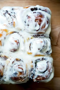 a cinnamon roll covered in icing on top of a wooden table