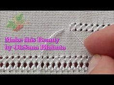 someone is stitching on the side of a white piece of fabric with a needle