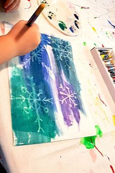 a child is painting on a canvas with watercolors