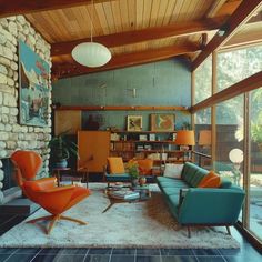 a living room filled with furniture and lots of windows next to a stone wall covered in bookshelves