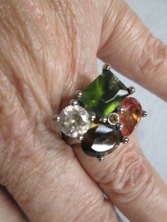 Stunning vintage 80's ring, new old stock. This is unique in as it's adjustable from about a size 6 1/2 to about a size 8 1/2, from inside the ring so you don't see it. Elegant faux stones with amazing earthy colors. You have yellows, greens, browns, and clear. Looks so rich! Measurements are about 15mm long by 20mm wide. Set in a pretty silver tone setting for a little added elegance. You will enjoy this for years to come. Silver Emerald Ring, Vintage Silver Rings, Blowout Sale, Faux Stone, Earthy Colors, Multi Stone Ring, Favorite Rings, Multi Stone, Art Deco Style