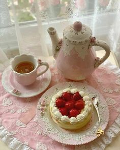 a cake with strawberries on it sitting next to a tea pot