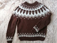 a brown and white sweater sitting on top of a bed