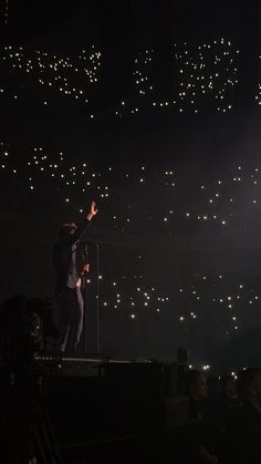 a man standing on top of a stage holding a microphone in front of a crowd