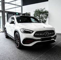 a white mercedes suv is parked in a showroom