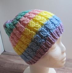 a white mannequin head wearing a multicolored knitted beanie hat