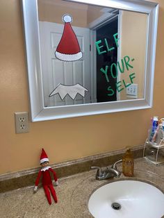 an elf's hat is on the mirror above a bathroom sink with a sign that says, help your self