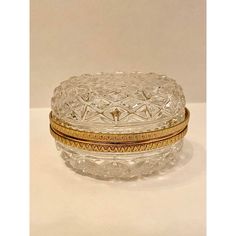 a clear glass box with gold trimmings on the lid and bottom, sitting on a white surface