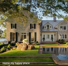 a large house with a pool in front of it and trees around the pond area