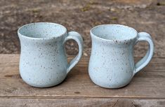 two blue mugs sitting on top of a wooden table