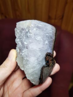 a person holding a piece of rock with ice crystals on it's surface in their hand