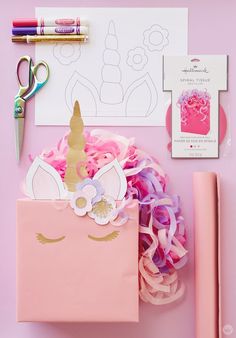 a pink box with a unicorn face on it next to some scissors and other crafting supplies