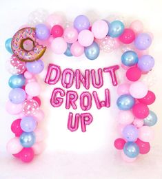 a donut grow up sign surrounded by balloons and confetti on a white background