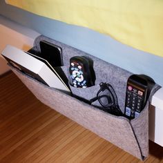 there is a cell phone and two remotes in the holder on the bed headboard