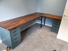 a corner desk with two drawers in an empty room next to a door and carpeted floor