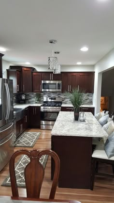 a kitchen with dark wood cabinets and stainless steel appliances is pictured in this image from the dining room