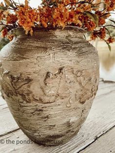 a vase with some flowers in it sitting on a wooden table next to the water