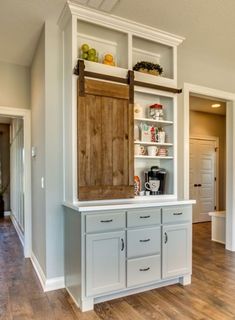 a kitchen with white cabinets and wood flooring in an open concept home, featuring hardwood floors