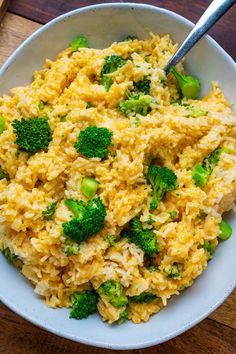 a white bowl filled with rice and broccoli on top of a wooden table