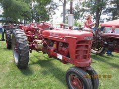 two red farmall tractors parked next to each other in the grass with trees behind them