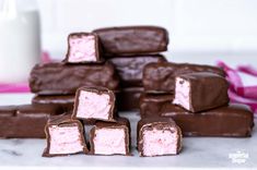 chocolate and pink marshmallows stacked on top of each other with a glass of milk in the background