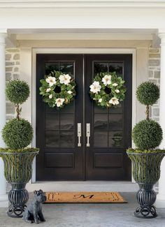 two potted plants with wreaths on them are sitting in front of a door