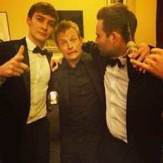 three men in tuxedos posing for the camera with one holding a beer bottle