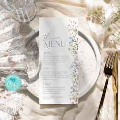 a plate with a menu on it next to some silverware and flowers in the background