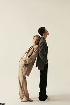 a man and woman standing next to each other in front of a white background,