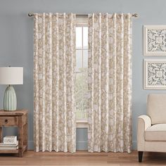 a living room with blue walls and white curtains on the window sill, beige chair and side table