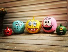 five painted pumpkins sitting on top of a wooden table