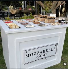 a table that has some food on top of it in front of a tree and grass area