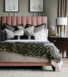 a bed with pink headboard and pillows on top of it next to two framed pictures