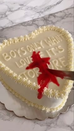 a heart shaped cake with a knife stuck in the middle and writing on it that says,