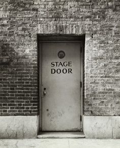 an old door with the words stage door on it in black and white, against a brick wall